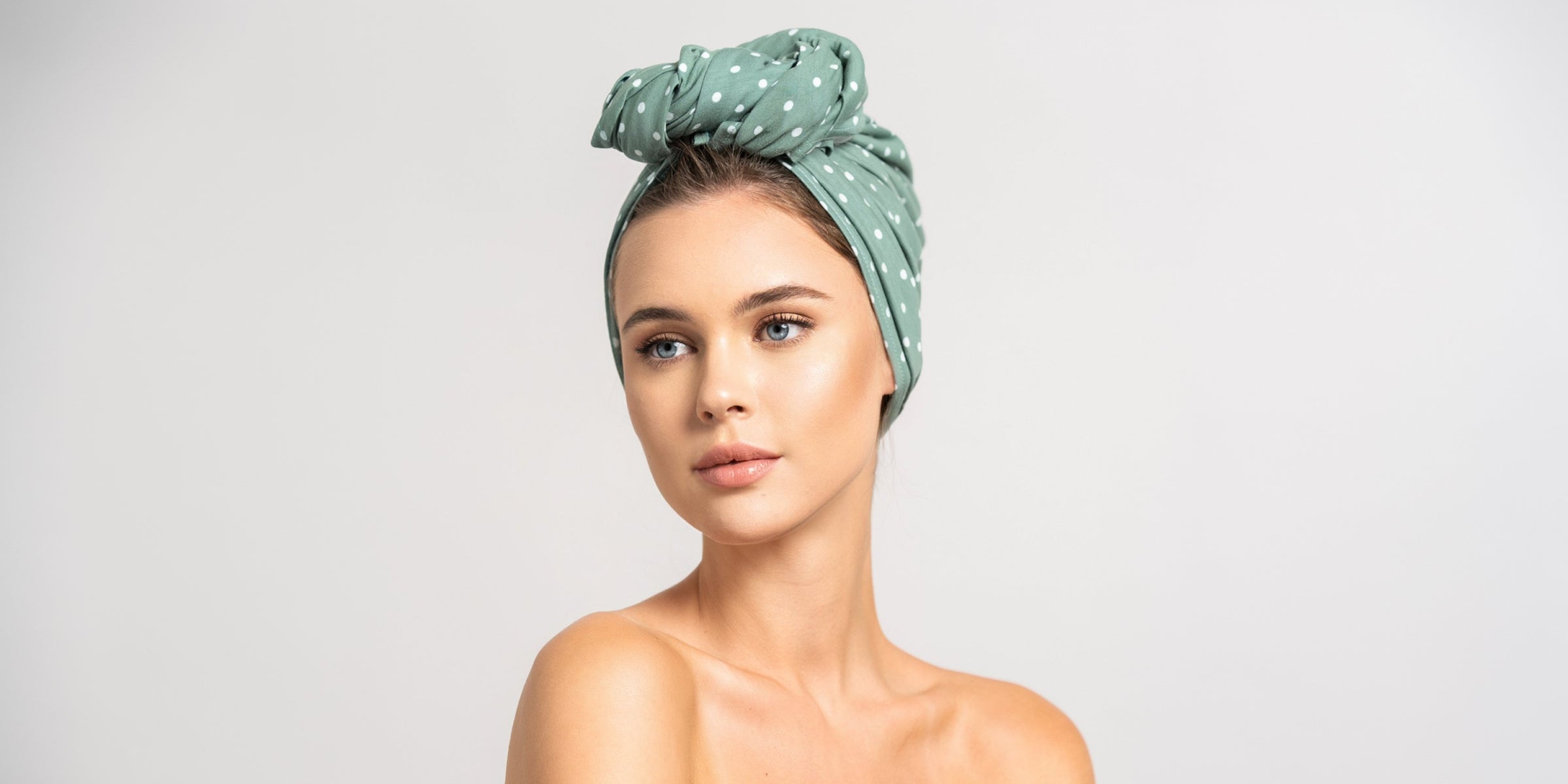 Schöne Frau mit blonden Haaren trägt ein Haar Handtuch aus Baumwolle in 55x120 von Curly N Covered als Turban gewickelt.