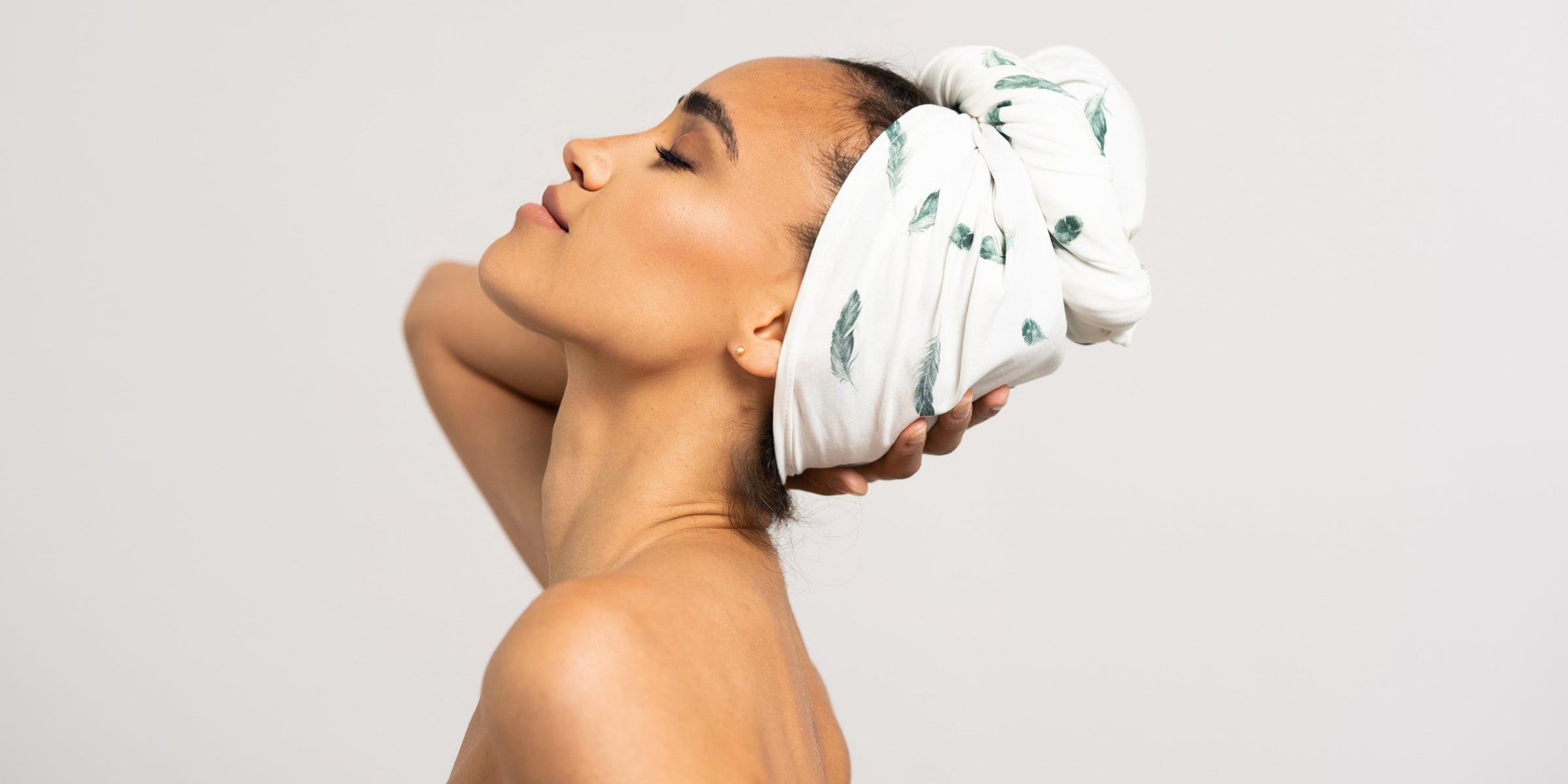 Schöne Frau mit dunklen Locken trägt eine Haar Handtuch aus Baumwolle in 70 x 180 von Curly N Covered als Turban gewickelt.