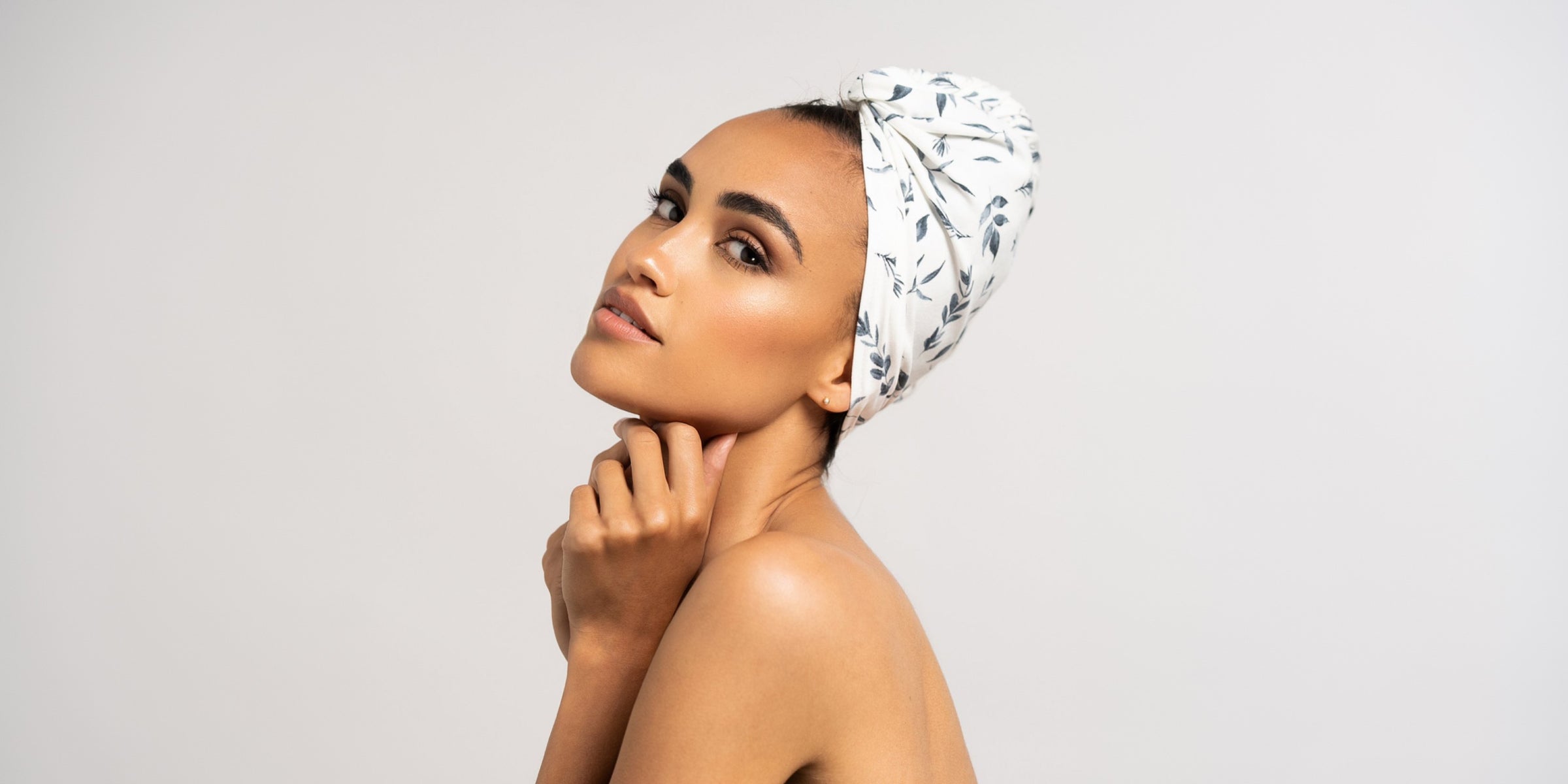 Wunderschöne Frau mit dunklen Locken trägt ein Haar Handtuch aus Baumwolle von Curly N Covered als Turban um ihre Haare gewickelt.
