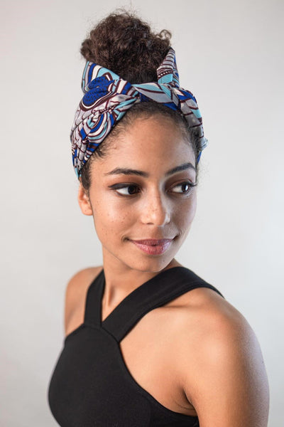Wunderschöne Frau mit dunklen Locken trägt einen African Head Wrap aus Wax Print (Baumwolle) in der Größe 30 x 85 von Curly N Covered in einem Muster aus weißen, blauen und türkisen Farben