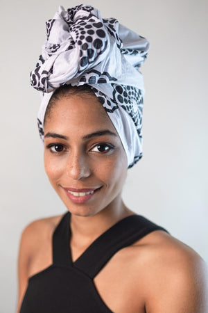 Wunderschöne Frau mit dunklen Haaren trägt ein afrikanisches Kopftuch in 58 x 180 aus Seersucker in Schwarz und Weiß von Curly N Covered als Head Wrap um die Haare.
