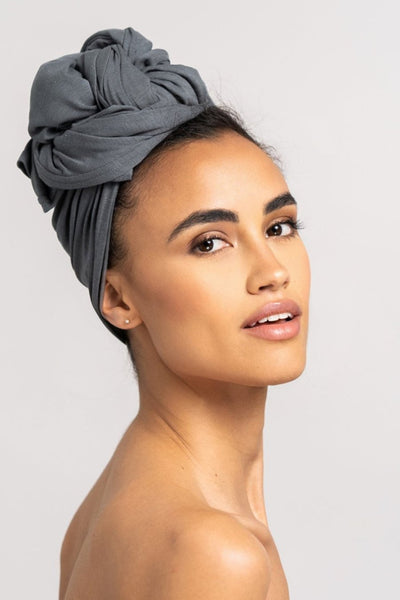 Seitenansicht von einer hübschen Frau, die ein graues Bambus Haar Handtuch von Curly'N'Covered als Turban trägt und dabei ihren Kopf in Richtung Kamera dreht