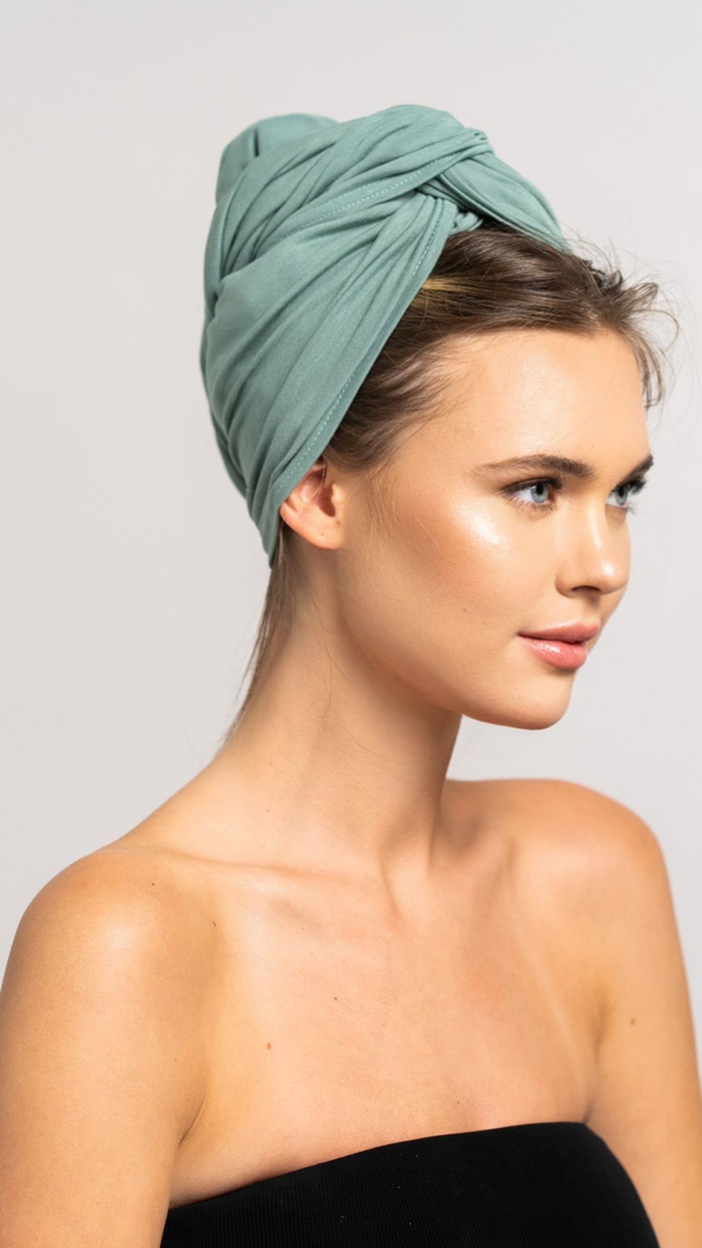 Seitliches Profil einer schönen Frau mit blonden Haaren, die ein mint grünes Bambus Haar Handtuch von Curly'N'Covered als Turban trägt