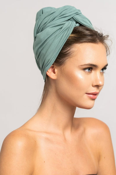 Seitliches Profil einer schönen Frau mit blonden Haaren, die ein mint grünes Bambus Haar Handtuch von Curly'N'Covered als Turban trägt