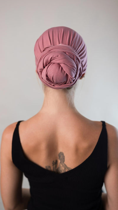 Rückansicht einer schönen Frau, die ein rosa Bambus Haar Handtuch von Curly'N'Covered als Turban trägt