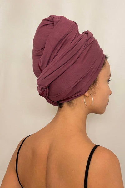 Schöne Frau mit dunklen Haaren trägt ein rotes Bambus Haar Handtuch in 70x180 von Curly'N'Covered als Turban gewickelt