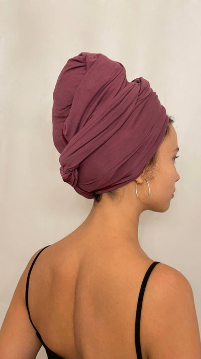 Schöne Frau mit dunklen Haaren trägt ein rotes Bambus Haar Handtuch in 70x180 von Curly'N'Covered als Turban gewickelt