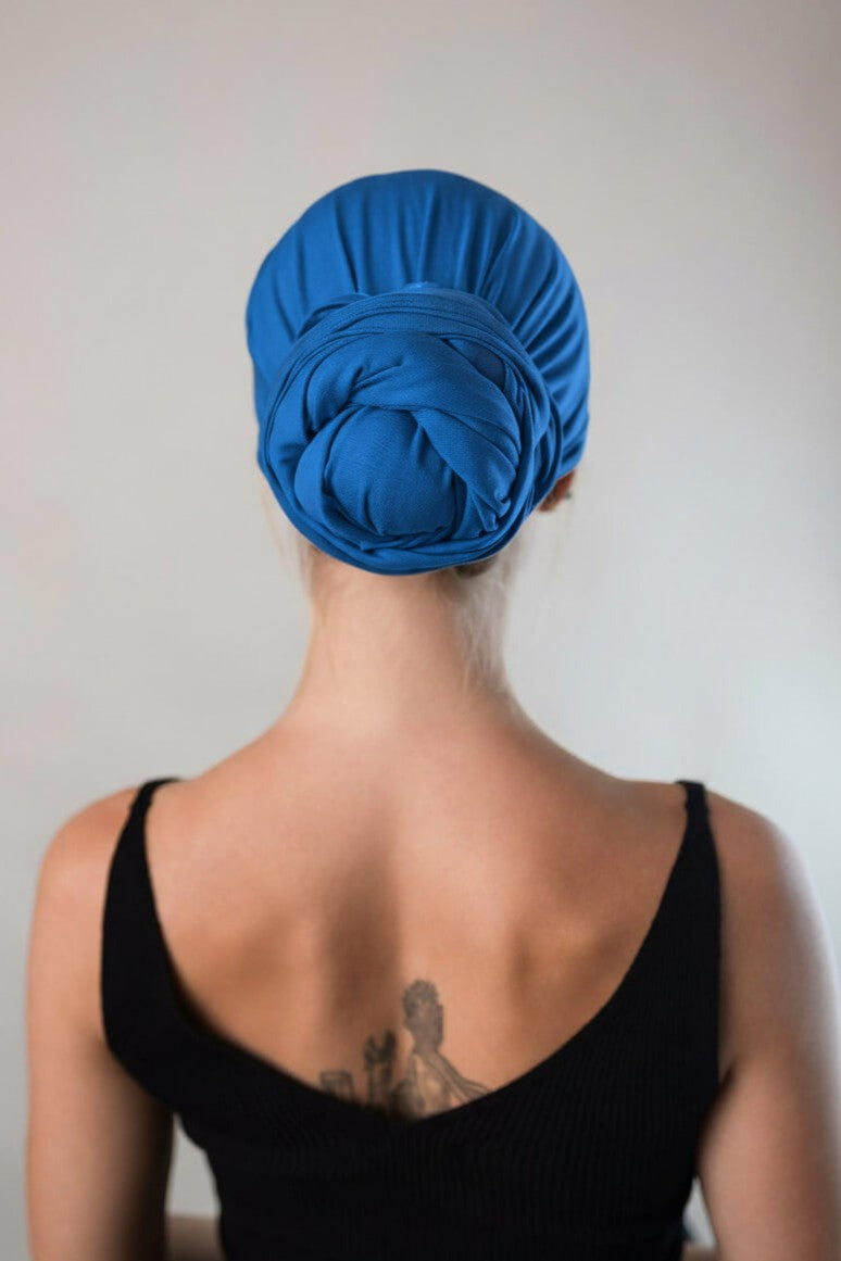 Rückansicht von einer hübschen Frau, die ein royalblaues Bambus Haar Handtuch von Curly N Covered als Turban trägt