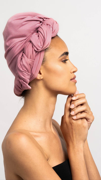 Bildhübsche Frau, die ein rosa Bambus Haar Handtuch von Curly'N'Covered als Turban trägt
