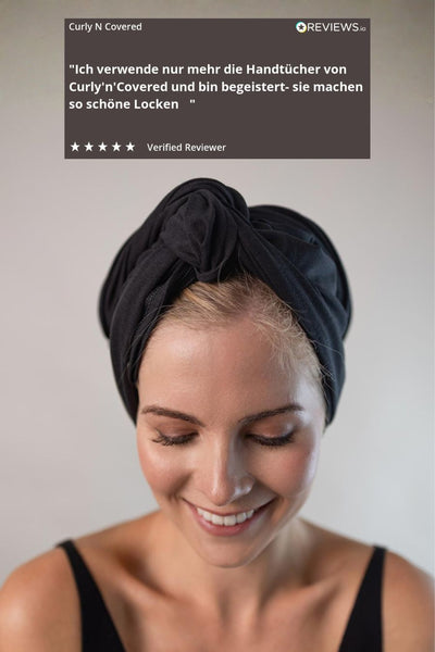 Wunderschöne Frau mit blonden Haaren trägt ein schwarzes Bambus Handtuch von Curly N Covered um ihre Haare zu ploppen.