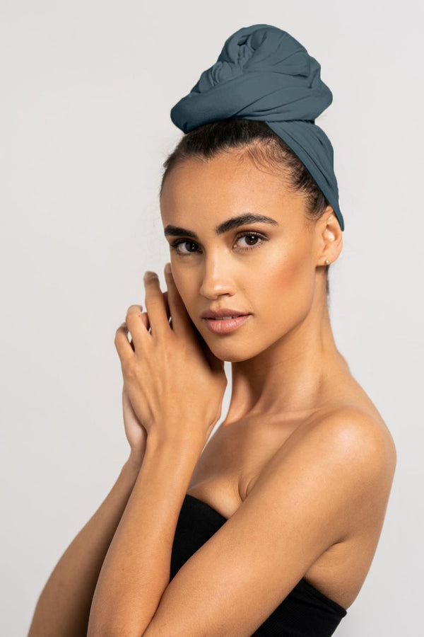 Wunderschöne Frau mit dunklen Haaren trägt ein stahl blaues Bambus Locken Handtuch von Curly N Covered als Turban gewickelt