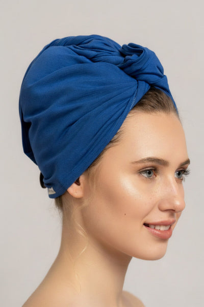 Bildschöne Frau trägt royal blaues Bambus Turban Handtuch von Curly N Covered als Turban gewickelt um ihre Haare zu ploppen