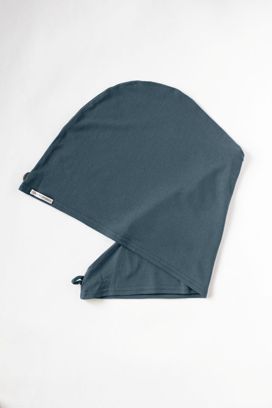 Bambus Turban Handtuch mit Kokosnussknopf in stahlblau von CURLY N COVERED, einmal gefaltet auf weißem Hintergrund