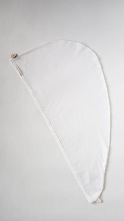 Bambus Turban Handtuch mit Kokosnussknopf in weiß von Curly'N'Covered, ausgebreitet auf weißem Hintergrund