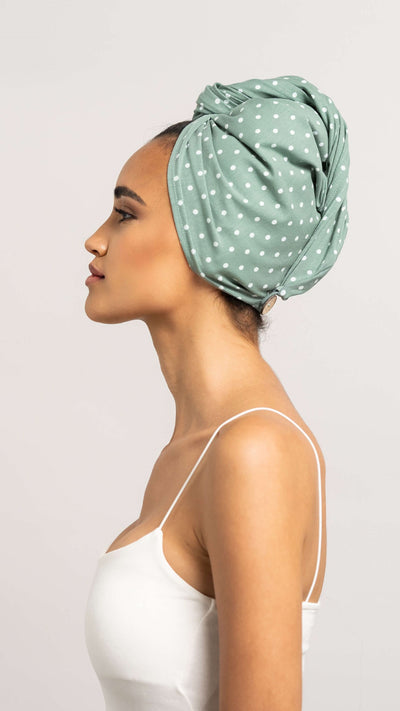 Seitliches Profil einer wunderschönen Frau, die einen hellgrünen Turban mit weißen Punkten aus Baumwolle trägt. Der Kokosnuss Knopf am hinteren Ende des Turbans ist zu erkennen.