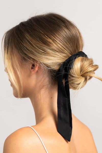 Wunderschöne Frau mit blonden Haaren trägt ein Haarband aus Baumwollseide in schwarz von CURLY N COVERED um ihren Dutt