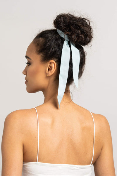 Wunderschöne Frau mit dunklen Locken trägt ein Haarband in hell blau aus Baumwollseide von CURLY N COVERED um ihren Dutt