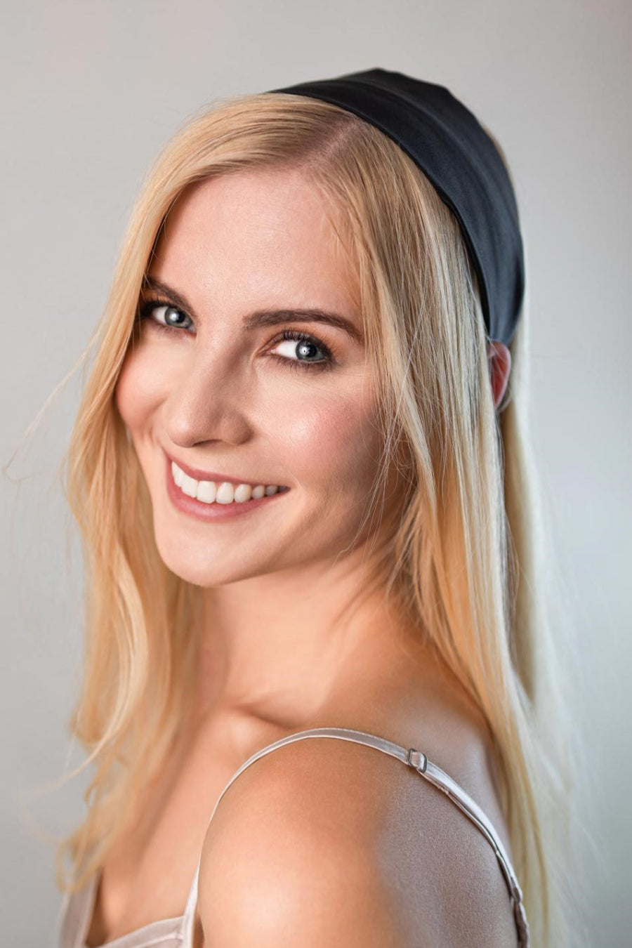 Schöne Frau mit langen blonden Haaren trägt ein elegantes breites Haarband in Schwarz aus reiner Maulbeer-Seide von Curly N Covered als Stirnband