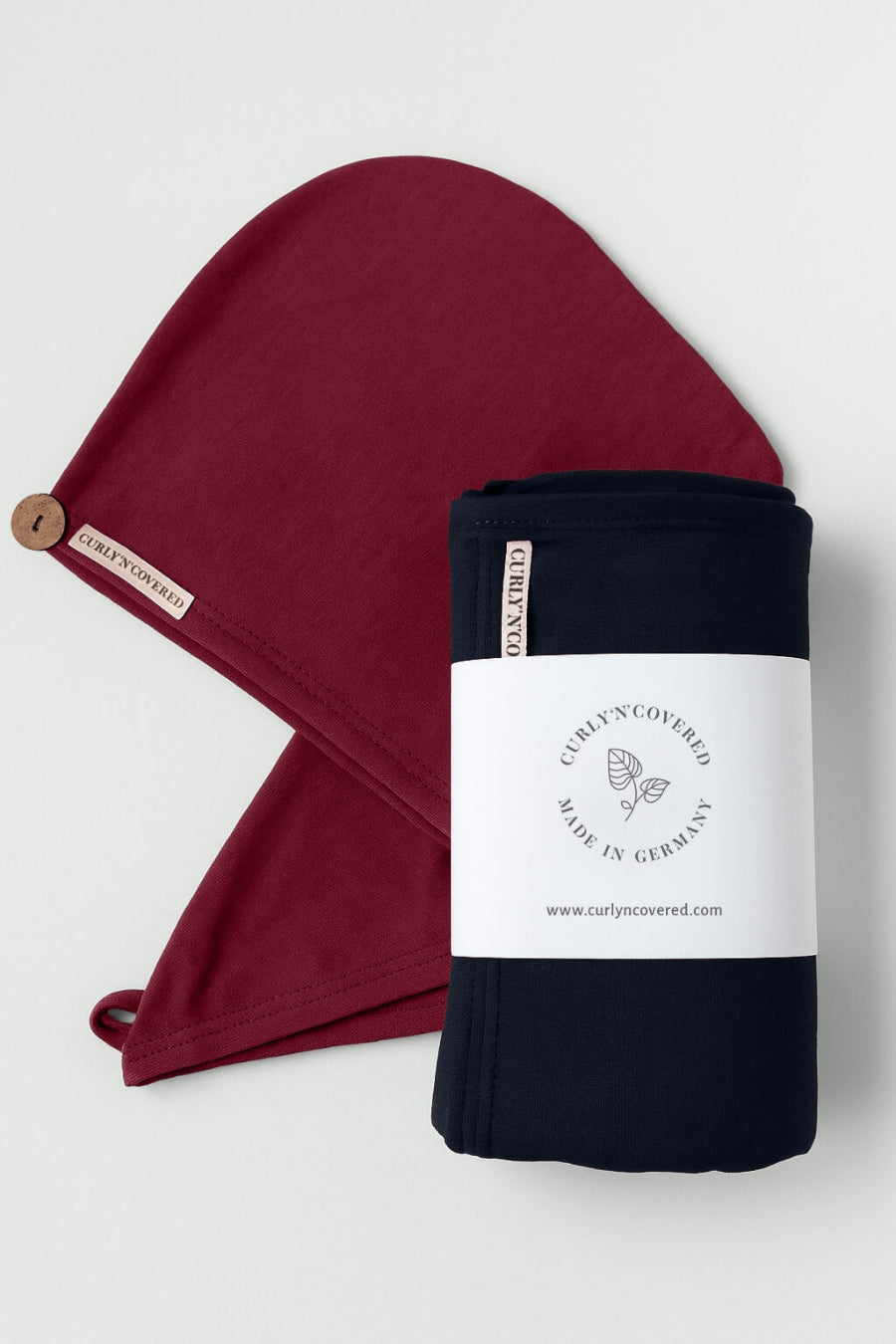 Ein Bundle aus schwarzem Haarhandtuch und bordeaux farbenem Turban Handtuch von CURLY N COVERED vor weißem Hintergrund