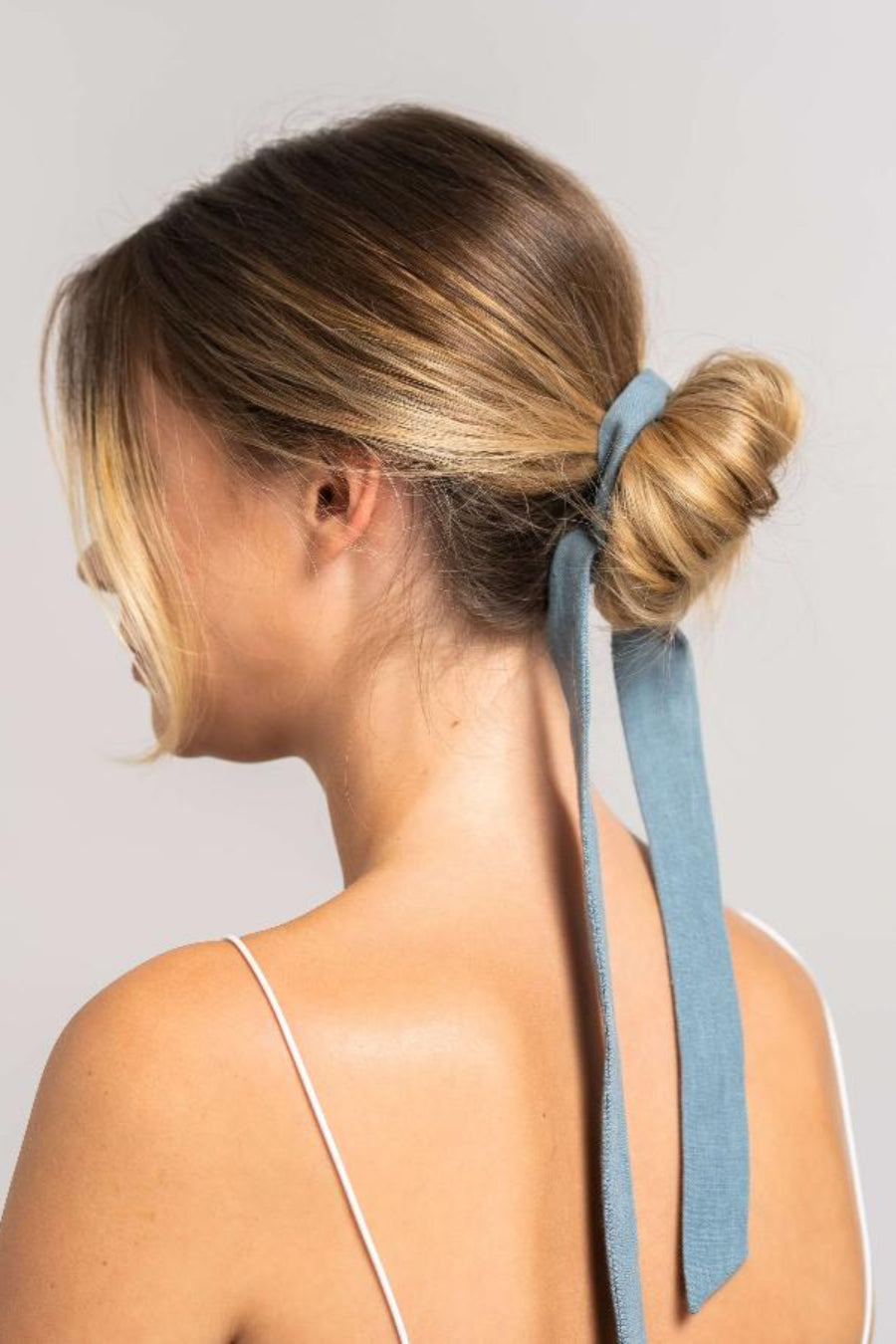 Bildschöne Frau mit langen blonden Haaren hat ein blaues Haarband aus Leinen von CURLY N COVERED in ihre Haare gebunden.
