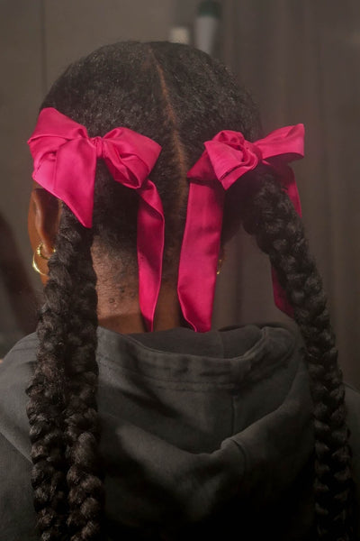 Wunderschöne Frau mit Afrohaaren hat Seidenschals für Damen aus reiner Maulbeer-Seide in Magenta von Curly N Covered als Schleife um ihre Zöpfe gebunden.