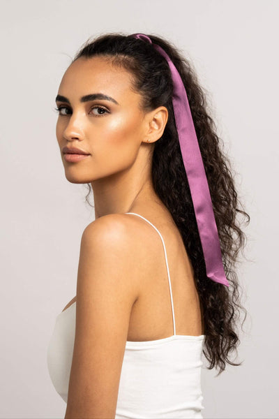 Schöne Frau mit langen dunklen Locken hat einen Seidenschal für Damen in Pflaume von Curly N Covered in ihre Haare geflochten.