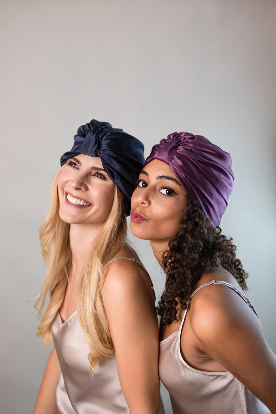 Zwei wunderschöne Frauen tragen Seidenturbane aus reiner Maulbeerseide von CURLY N COVERED zum Schutz ihrer Haare und Locken