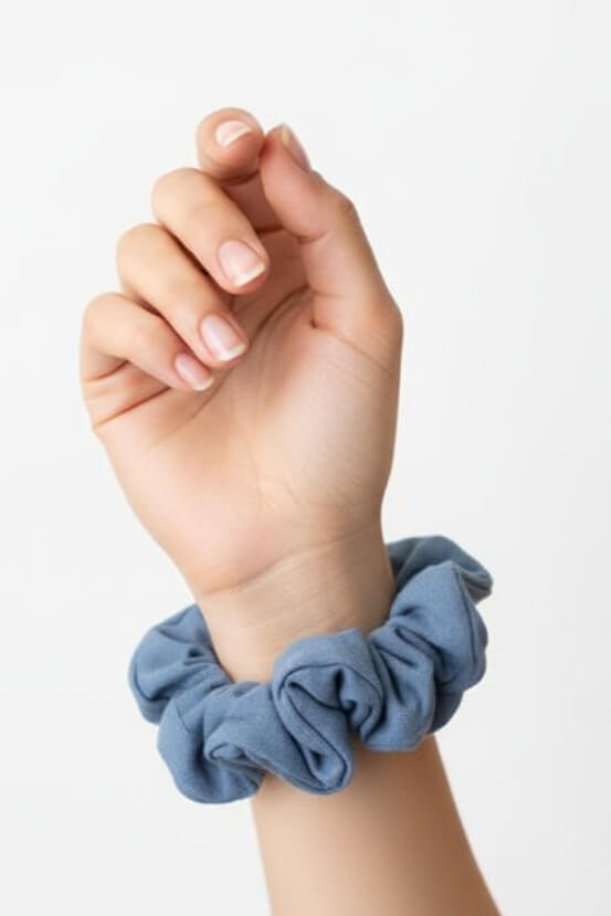 Ein blauer Scrunchie aus Bambus-Stoff von Curly N Covered als Accessoire am Handgelenk