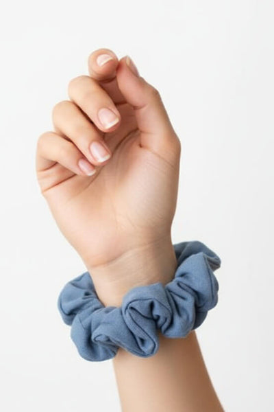 Ein blauer Scrunchie aus Bambus-Stoff von Curly N Covered als Accessoire am Handgelenk