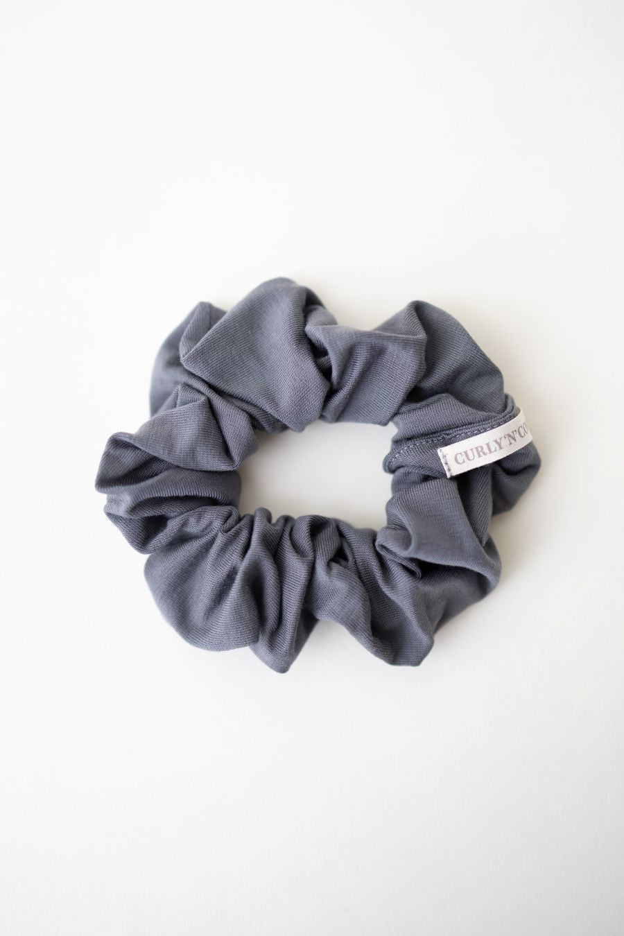 Ein Scrunchie aus weichem Bambus Stoff in Grau von Curly N Covered vor weißem Hintergrund
