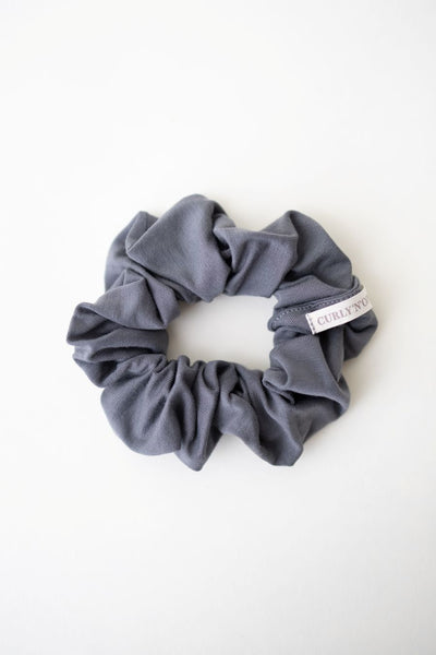 Ein Scrunchie aus weichem Bambus Stoff in Grau von Curly N Covered vor weißem Hintergrund