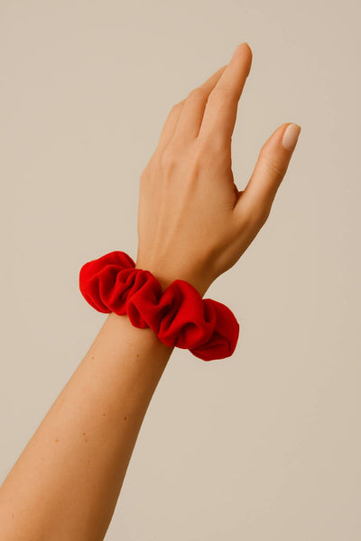 Ein mohn roter Scrunchie aus Bambus-Stoff von Curly N Covered als Accessoire am Handgelenk