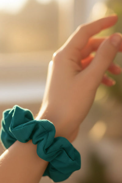 Ein petrol farbener Scrunchie aus Bambus-Stoff von Curly N Covered als Accessoire am Handgelenk