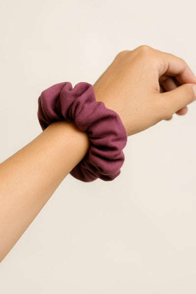 Ein roter Scrunchie aus Bambus-Stoff von Curly N Covered als Accessoire am Handgelenk