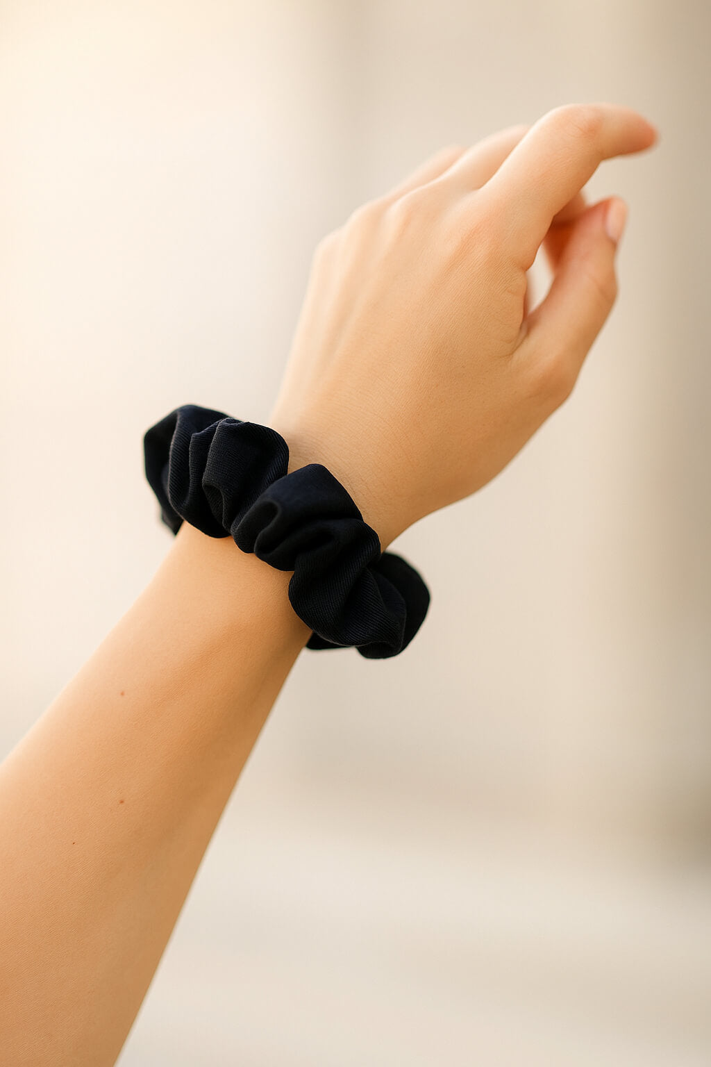 Ein schwarzer Scrunchie aus Bambus-Stoff von Curly N Covered als Accessoire am Handgelenk