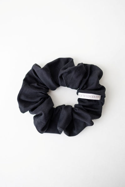 Ein Scrunchie aus weichem Bambus Stoff in zeitlosem Schwarz von Curly N Covered vor weißem Hintergrund