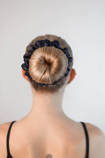 Schöne Frau mit blonden Haaren trägt einen Scrunchie aus reiner Maulbeer-Seide in marine blau von Curly N Covered im Haar