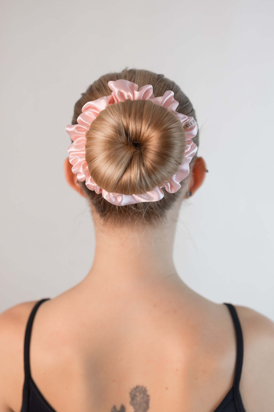 Schöne Frau mit blonden Haaren trägt einen Scrunchie aus reiner Maulbeer-Seide in zart rosa von Curly N Covered im Haar