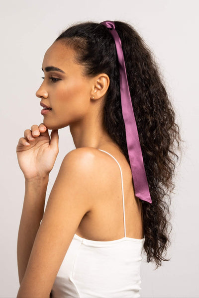 Bildschöne Frau mit langen dunklen Locken hat einen Seidenschal für Damen in Pflaume von Curly N Covered in ihre Haare geflochten.