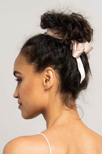 Wunderschöne Frau mit dunklen Locken trägt ein sandfarbenes Haarband aus 100% Maulbeerseide von CURLY N COVERED um ihren Dutt