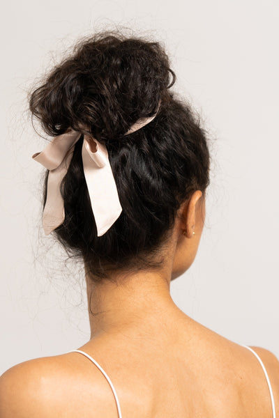 Bildschöne Frau mit dunklen Locken trägt ein sandfarbenes Haarband aus 100% Maulbeerseide von CURLY N COVERED um ihren Dutt