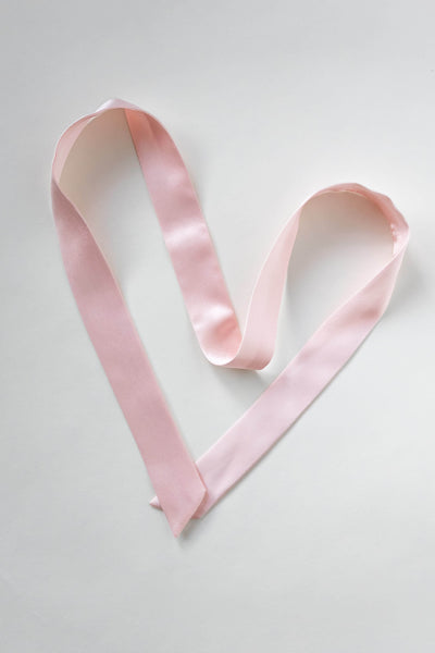 Seidenschal aus reiner Maulbeerseide in rosa von Curly N Covered vor weißem Hintergrund als Herz ausgelegt