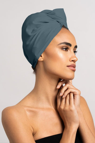 Schöne Frau trägt stahl blaues Bambus Turban Handtuch mit Kokosnussknopf von CURLY N COVERED als Turban gewickelt, perfekt für die Plopping Methode
