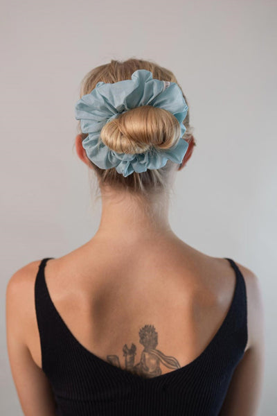 Wunderschöne Frau mit blonden Haaren trägt einen hell blauen XXL Scrunchie aus Cotton Silk (Baumwolle und Seide) von Curly N Covered im Haar.